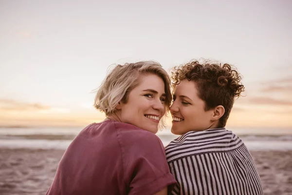 Portrait Smiling Young Lesbian Couple Looking Shoulders While Sitting Sandy — Stock Photo, Image