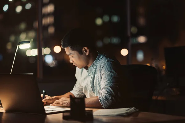 Joven Empresario Asiático Escribiendo Cuaderno Mientras Trabaja Escritorio Una Oscura — Foto de Stock