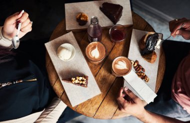 Farklı bir grup genç arkadaşlar birlikte bir ürün yelpazesine tatlılar ve kahve keyfini bir Cafe masa etrafında oturmuş yüksek açı