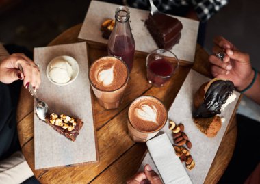 Bir grup birlikte lezzetli tatlılar ve kahve bir ürün yelpazesine sahip bir Cafe masa etrafında oturup farklı genç arkadaşlar yüksek açı