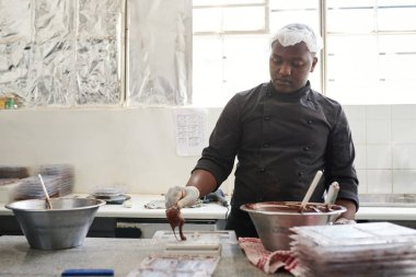 Zanaat bir çikolata fabrikası kalıplara eritilmiş çikolata dökme bir masada duran işçi