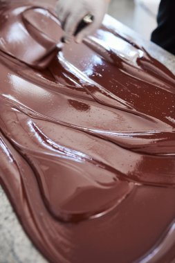 Bir spatula ile bir tablo üzerinde çikolata dışarı erime yayılan bir zanaat çikolata yapım fabrika işçisi closeup 