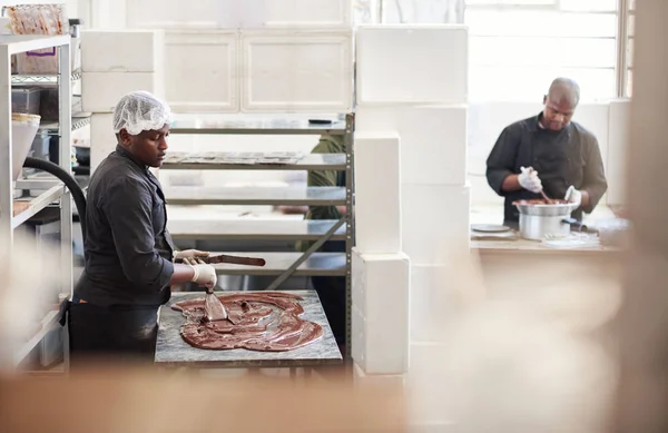 Afrikanischer Unternehmer Verteilt Schmelzende Schokolade Auf Einem Tisch Zum Abkühlen — Stockfoto