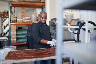 Fabrika zanaat bir çikolata içinde çalışırken bir masada çikolata dışarı erime yayılan işçi