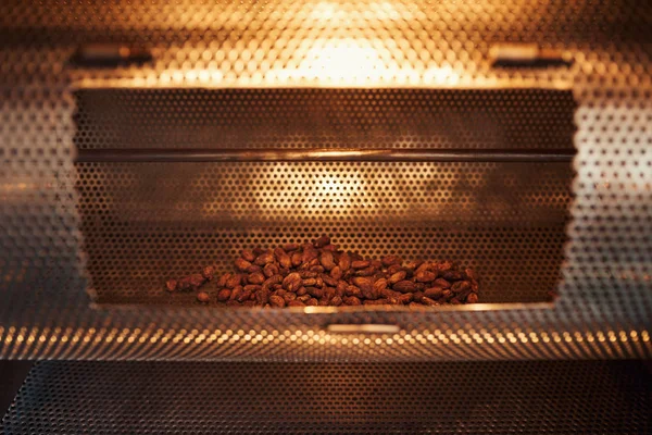 Closeup of a pile of cocoa beans being roasted in a machine in an artisanal chocolate making factory