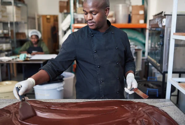 Arbeiter Der Mit Spachteln Schmelzende Schokolade Auf Einem Tisch Verteilt — Stockfoto
