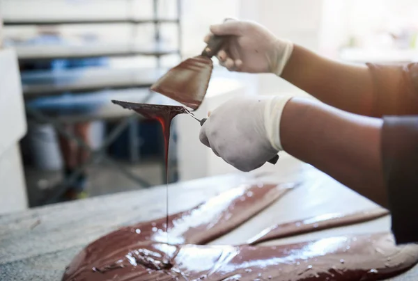 在手工巧克力制品厂工作时 一名工人将融化的巧克力与沙图拉混合在一起的特写镜头 — 图库照片