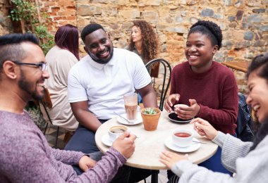 Avluda bir trendy Cafe birlikte kahve içerken sohbet bir masada oturan genç arkadaşlar gülümseyen farklı grup