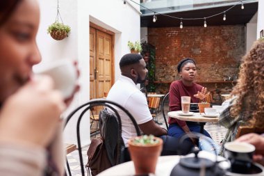 Kahveden sonra yoğun bir kafe avlusunda bir masada otururken arkadaşlarınızla konuşurken genç Afrikalı kadın