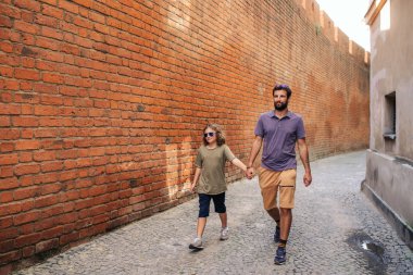 Baba ve genç oğlu el ele birlikte Arnavut kaldırımlı sokakları şehrin eski bir bölümünde boyunca yürüyüş
