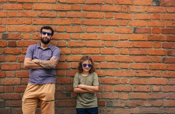 Father Son Looking Cool Wearing Sunglasses Leaning Red Brick Arms — Stock Photo, Image