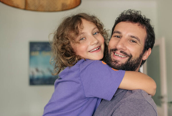 Счастливый отец-одиночка держит своего милого маленького сына на руках, веселясь вместе дома
