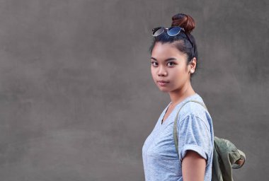 Yana doğru bir duvarın dışında önünde duran bir raslantı giyimli Genç Asyalı kadın görüntüsünü kapatmak