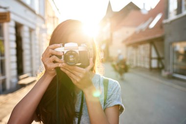 Öğleden sonra şehir etrafında yürürken vintage bir slr fotoğraf makinesi ile fotoğraf çekmek Genç Asyalı kadın