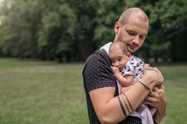 Onun bebek çocuk dışarıda duran bir parkta onun omzuna kucaklarken seven genç baba