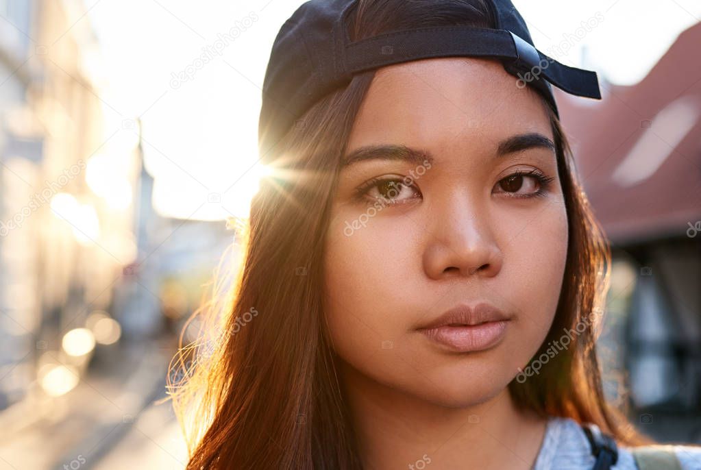 Close up portrait of a young Asian woman with an urban style and attitude walking around the city in the afternoon