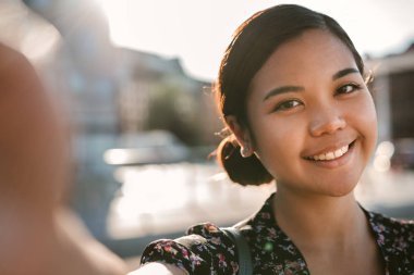 Selfies onun smartphone ile alarak güneşli bir günde dışarıda duran gülümseyen genç Asya Kolej Öğrenci portresi