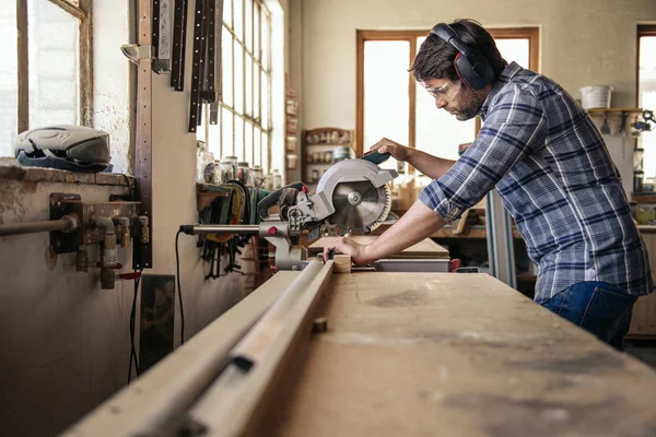 Der Gelernte Schreiner Mit Sicherheitsausrüstung Sägt Ein Stück Holz Mit — Stockfoto