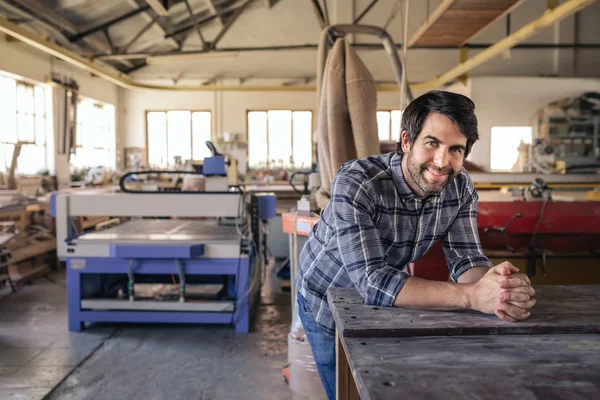 Retrato Marceneiro Sorrindo Enquanto Inclina Uma Bancada Seu Grande Estúdio — Fotografia de Stock