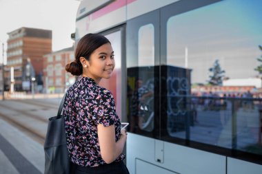 Şehirde çalışıyorum süre commuting bir otobüs yaklaşık binmeye bir gülümseyen Genç Asyalı işkadını portresi