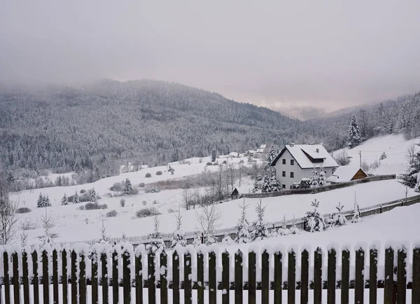 Scenic view of chalets on a hill in a snow covered landscape in the middle of the wintertime