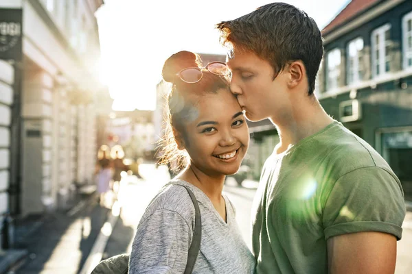 午後には街で一緒に立っている彼氏に額にキスされている笑顔の若い女性の肖像画 — ストック写真