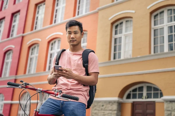 도시에서 화려한 자전거에 핸드폰에 텍스트를 보내는 아시아 남자의 초상화 — 스톡 사진