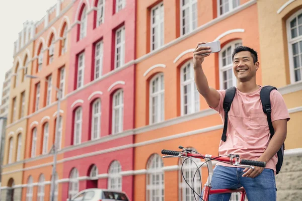 Sonriente Joven Asiático Tomando Una Selfie Mientras Está Sentado Bicicleta —  Fotos de Stock