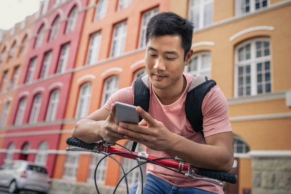 Joven Asiático Sentado Bicicleta Frente Coloridos Edificios Ciudad Enviando Mensaje — Foto de Stock