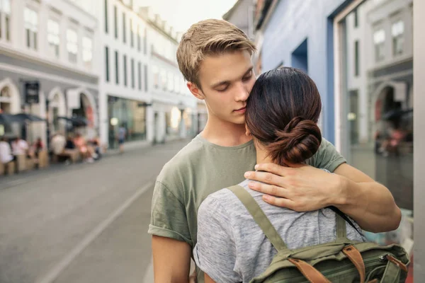 下午晚些时候 一个闭着眼睛抱着女友的年轻人站在一条城市街道上 — 图库照片