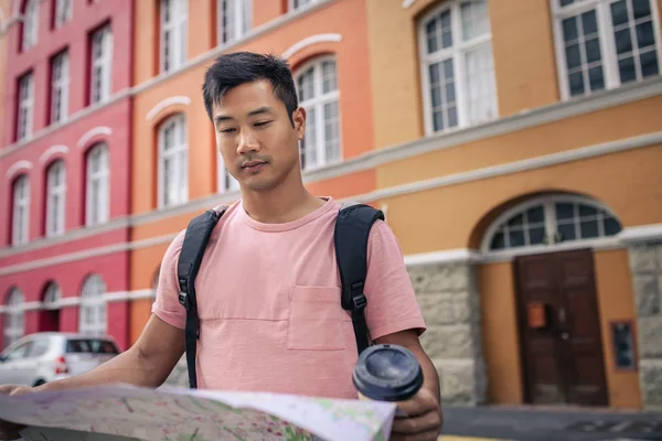 Ung Asiatisk Man Dricker Takeaway Kaffe Och Läsa Karta För — Stockfoto