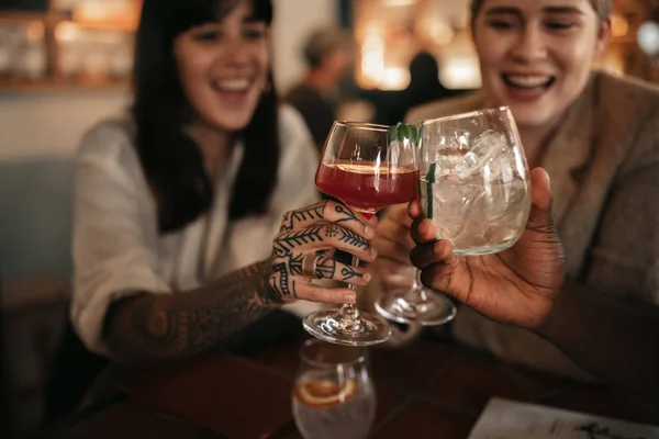 一群面带微笑的年轻朋友在酒吧的一张桌子上敬酒 并喝着饮料 他们的特写镜头 — 图库照片