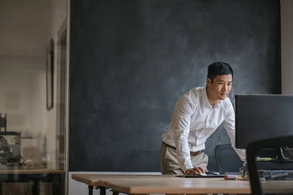 Сосредоточенный Молодой Азиатский Бизнесмен Работающий Компьютером Своим Столом Перед Пустой — стоковое фото