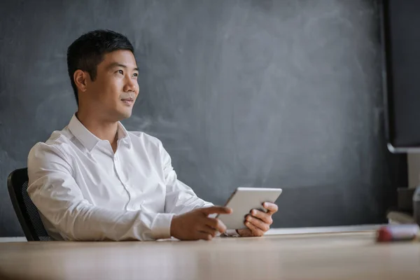 Молодой Азиатский Бизнесмен Смотрит Глубоко Мысли Работая Над Цифровым Планшетом — стоковое фото