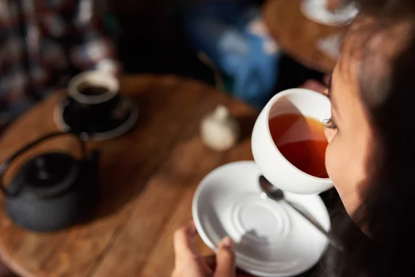 Junge Frau Nippt Einer Tasse Tee Während Sie Einem Cafétisch — Stockfoto