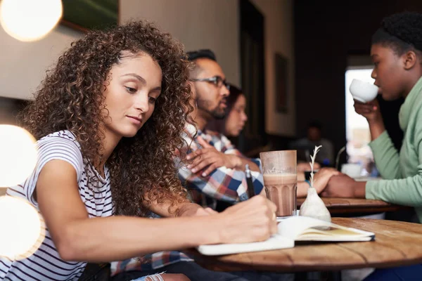 Glimlachende Jonge Vrouw Met Krullend Haar Schrijven Een Boek Terwijl — Stockfoto