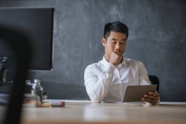 Ofiste dijital tablet kullanarak genç bir Asya işadamı portresi