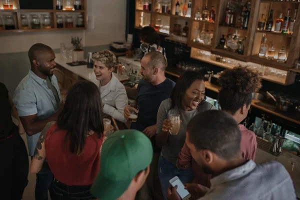 一群不同的年轻人晚上站在酒吧里喝酒时一起交谈 — 图库照片