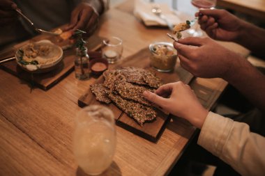 Modaya uygun bir barda bir masada birlikte otururken yemek paylaşan bir grup genç arkadaşın yakın çekimi