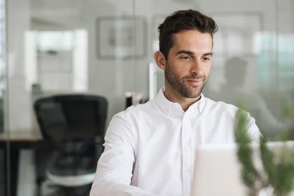 Joven Hombre Negocios Sonriendo Mientras Está Sentado Solo Escritorio Una — Foto de Stock