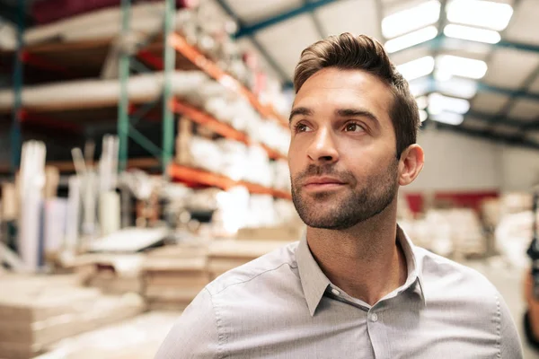 Smiling manager standing on the warehouse floor with stacks of carpets and textiles on shelves in the background