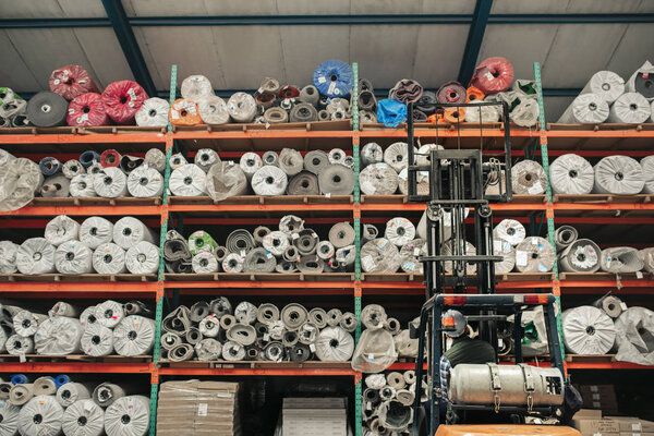 Вид сзади водителя-фордовца, осторожно снимающего приклад с полок во время работы на полу большого ковра.
