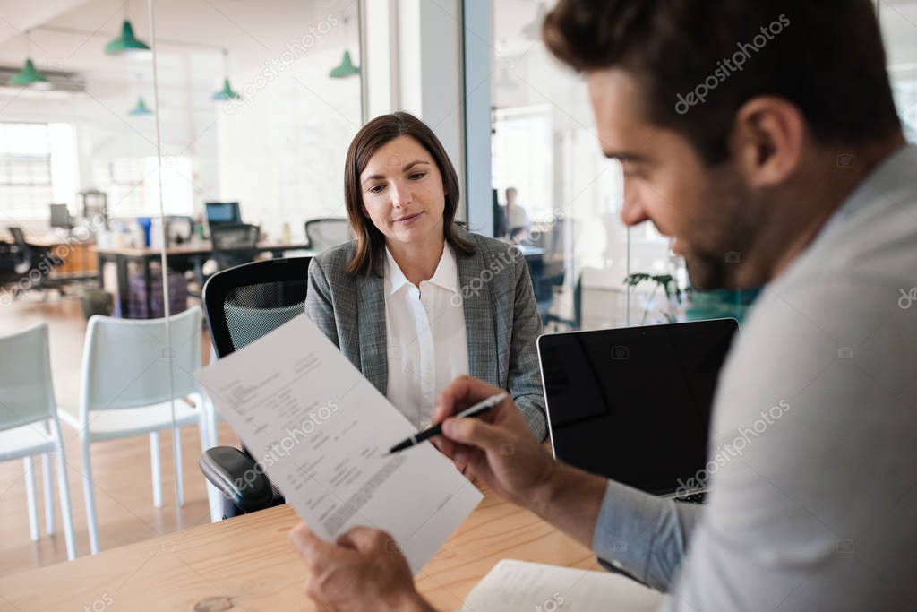 Smiling manager reading a resume during an interview with a potential new employee in his office