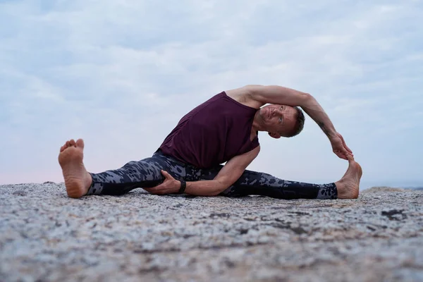 Fitter Mann Beim Drehen Von Kopf Bis Knie Während Yoga — Stockfoto