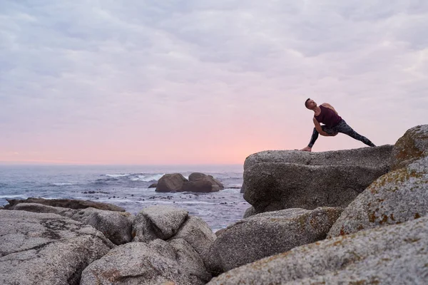 适合男人做八角姿势 同时在海边的岩石上练习瑜伽 在黄昏时分面对戏剧性的天空 — 图库照片