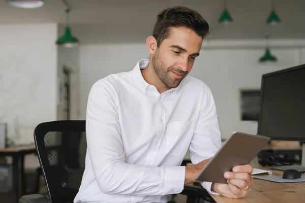 Joven Hombre Negocios Sonriendo Sentado Escritorio Una Gran Oficina Moderna — Foto de Stock