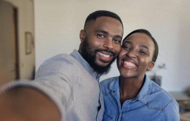 Gülümseyen genç Afro-Amerikan çift evde oturma odasında birlikte selfie çekerken ayakta