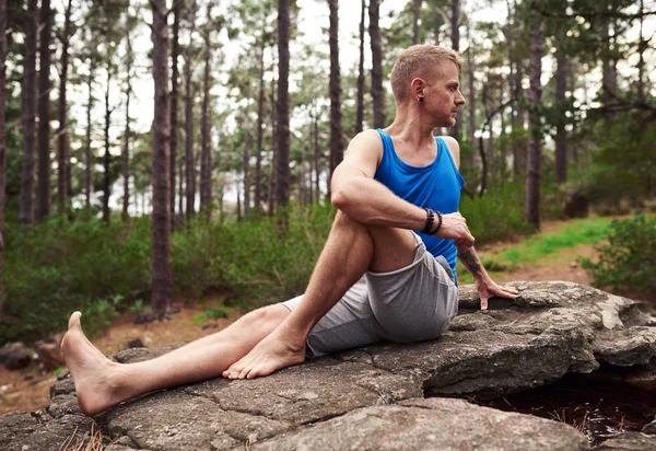 Man Sitting Rocky Outcrop Pine Forest Doing Seated Spinal Twist — Stock Photo, Image