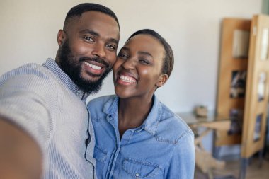 Gülümseyen genç Afro-Amerikan çift evde oturma odasında birlikte selfie çekerken ayakta