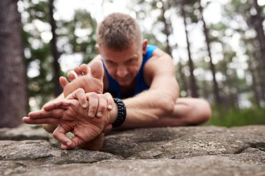 Fit adam yoga yaparken diz poz baş yapıyor bir çam ormanında bir kaya üzerinde oturan